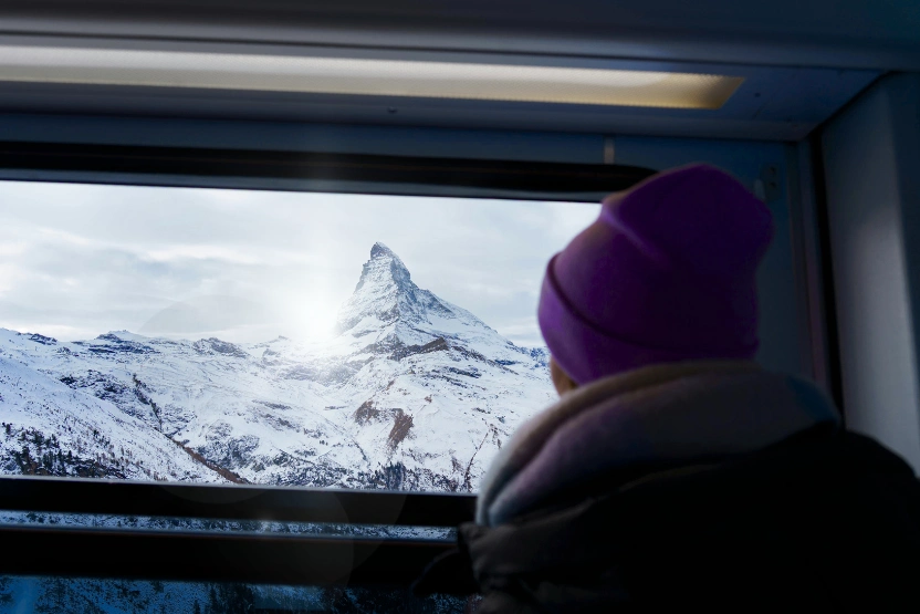 Passenger on a train, looking out the window at a snowy mountain