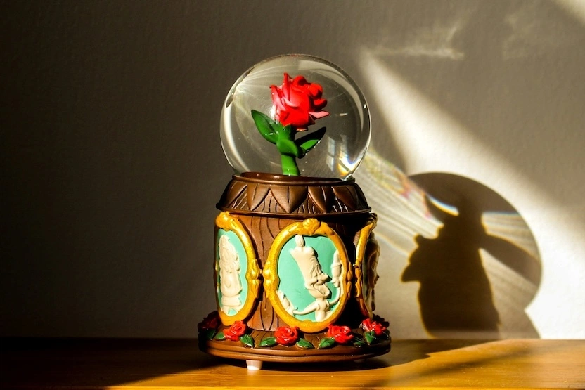 A Beauty and the Beast globe on a dresser.