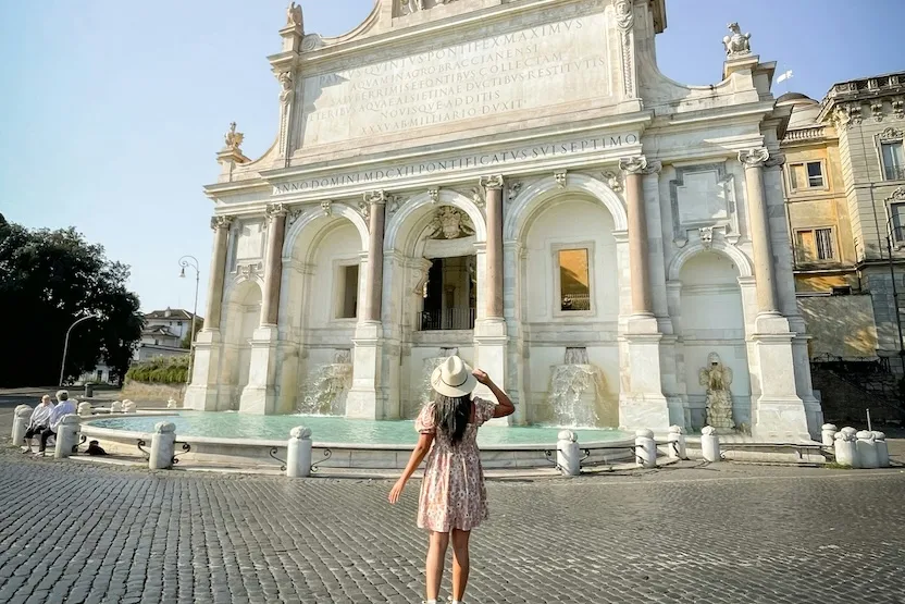 A female tourist in a white hat and sundress, exploring Rome.