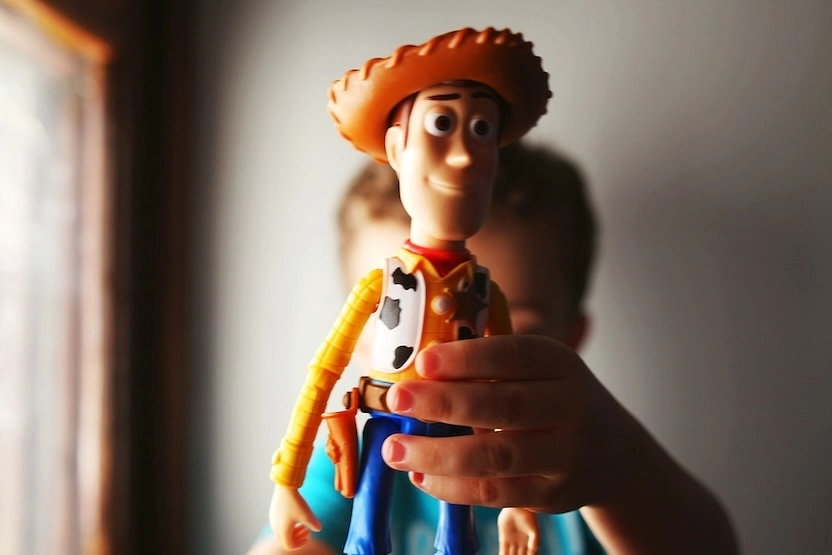 A child holding up a Toy Story toy.