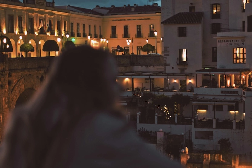 A woman looking at a courtyard in Ronda, Spain, at night.