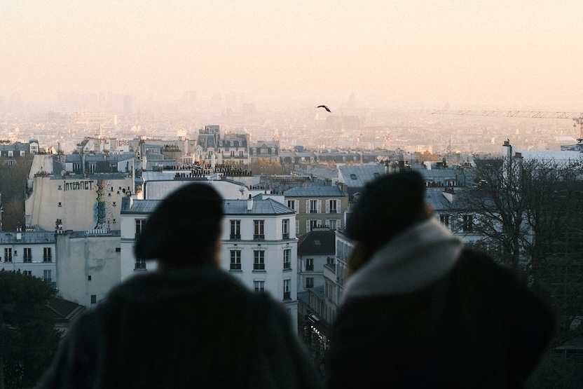 Two tourists looking out at the city of Paris.