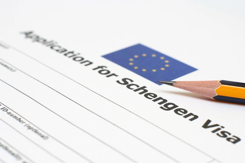 A printed Schengen visa application with a sharpened pencil on top.