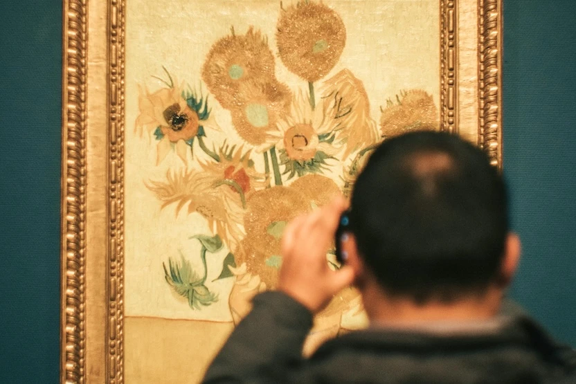 A museum guest taking a photo of the Van Gogh Sunflowers.