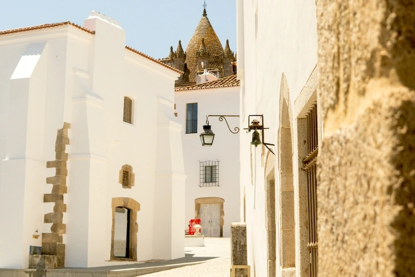 White and stone buildings on a narrow street in Évora, Portugal.