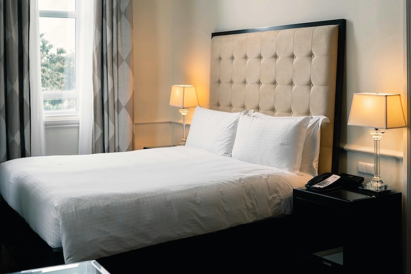 Hotel room with warm lighting, bed, and two lamps