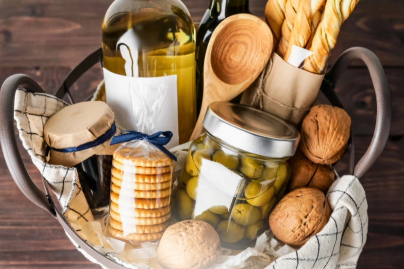 A fully stocked gift basket with olives, crackers, jam, wine, and more