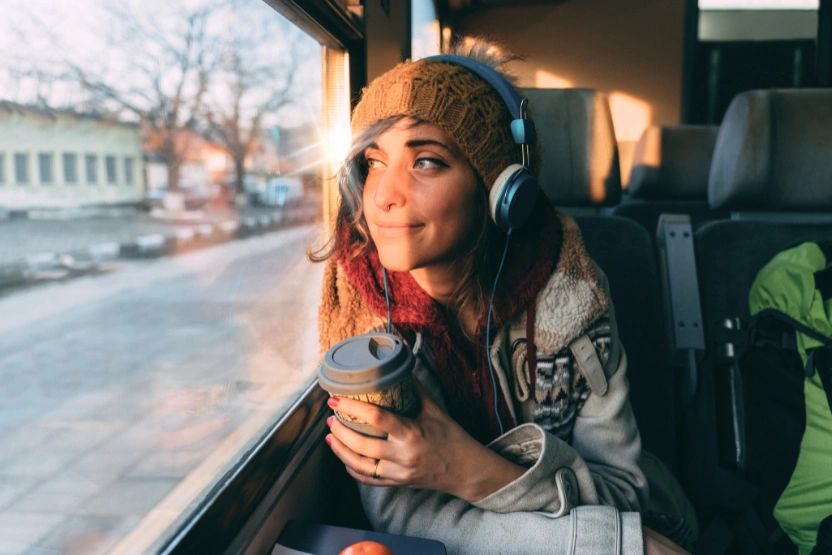 Woman with headphones and coffee on a train