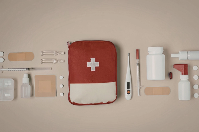 First aid kit flat lay on a tan background
