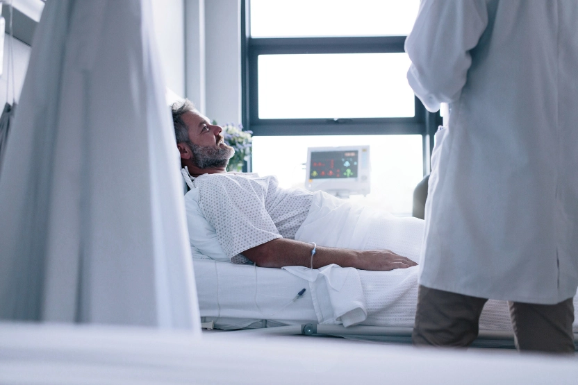 Man in a hospital bed, talking to the doctor