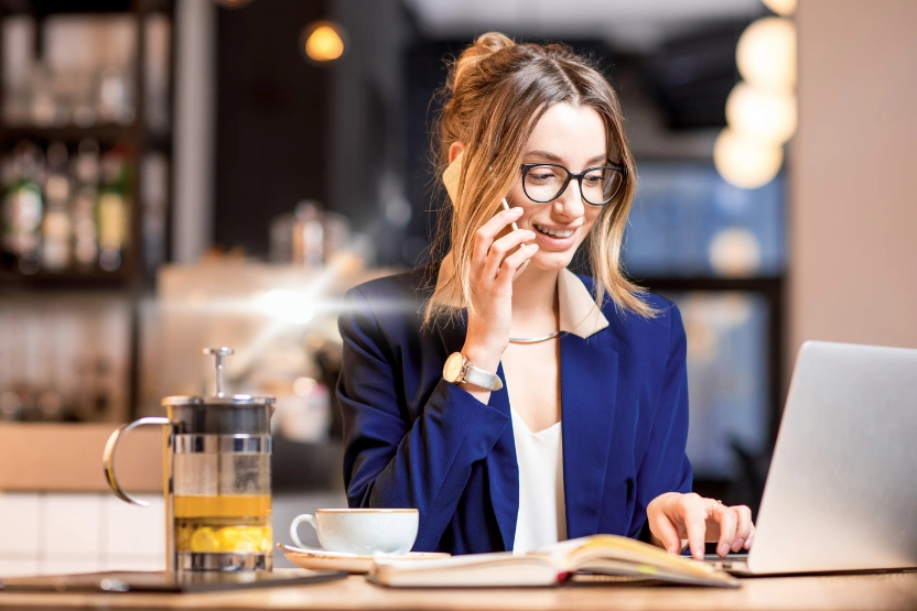Woman in a blue blazer working remotely at a cafe