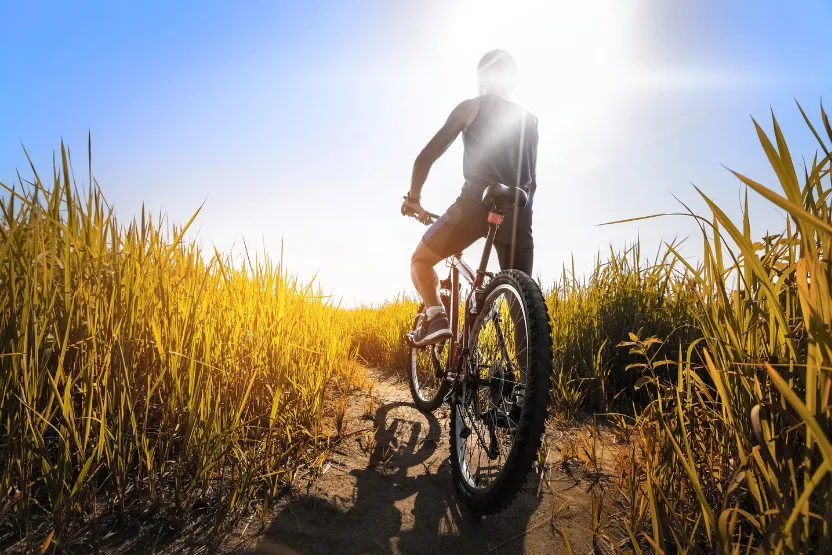 Male cyclist on a rural trail in mid afternoon sun